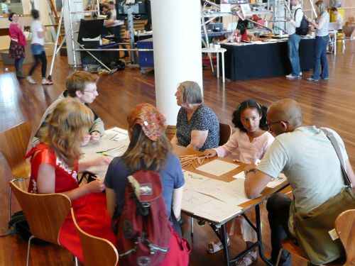 Five people sitting around a table and drawing.