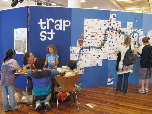 A table with children around it, and a large felt map on the wall behind.