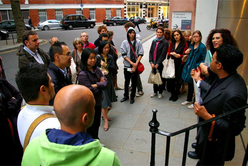 Two tour guides standing on steps, talking to an assembled group